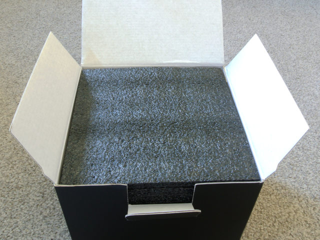 The box lid has been opened and there is a top lining of dark grey foam material