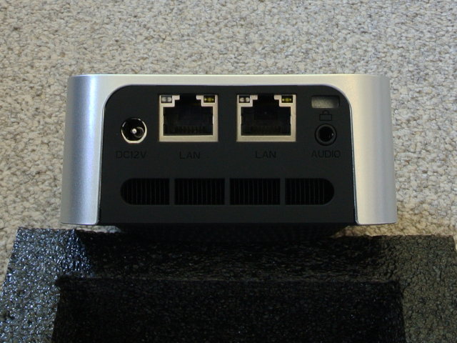 Posterior view. This has a black plastic inset into the silver top case. On the left is a round barrel socket. Medially are 2 side-by-side ethernet ports. To the right is a 3.5mm audio socket and just above this is a Kensington lock